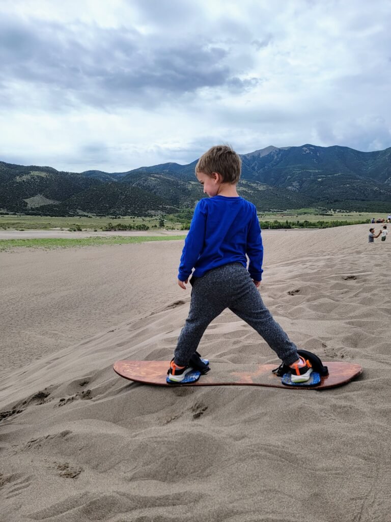 cooper sand boarding at great sand dunes. a close second for the best national parks to visit with kids